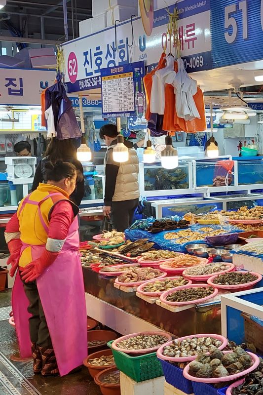 A lady views her shellfish display at Ulsan traditional market, South Korea