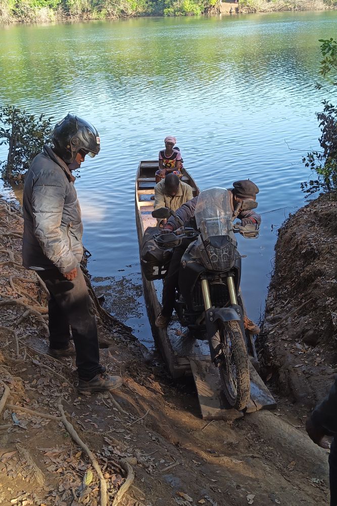 Motorcycle being loaded in wooden canoe to cross river in Guinea